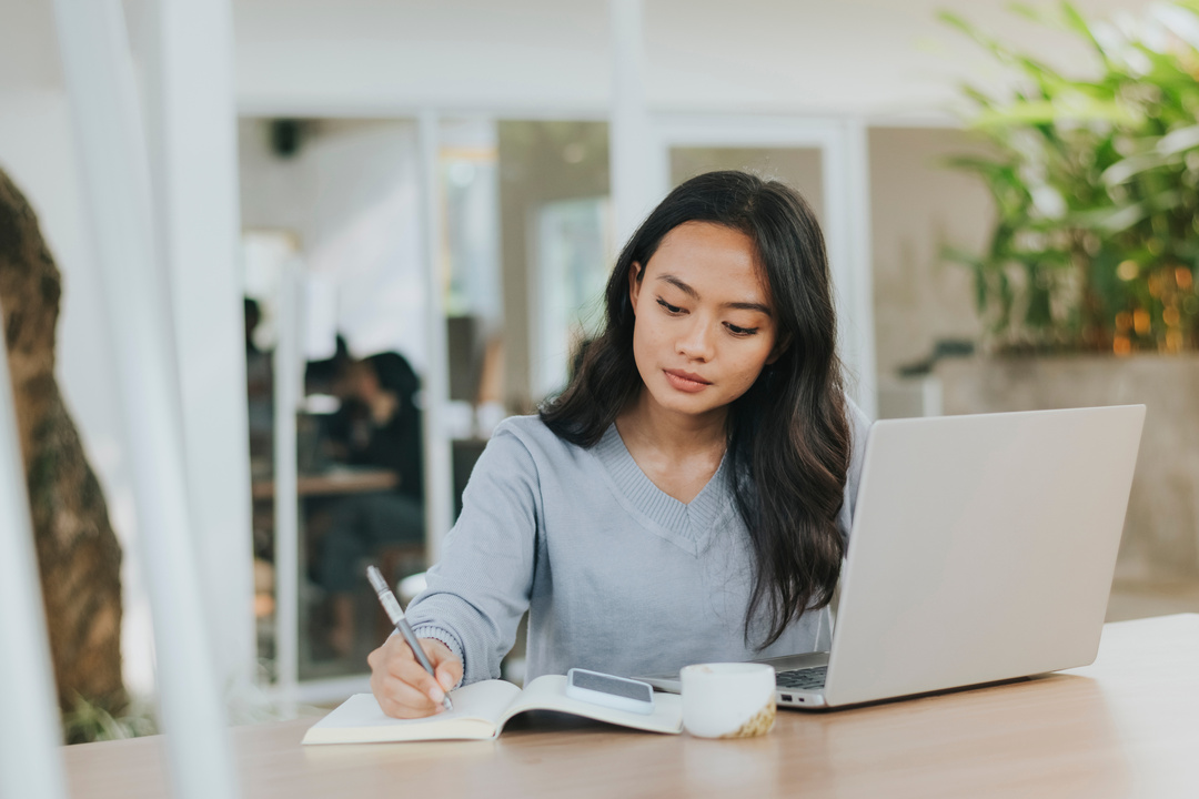 Woman Writing on Her Notebook and Using Her Laptop Outdoors